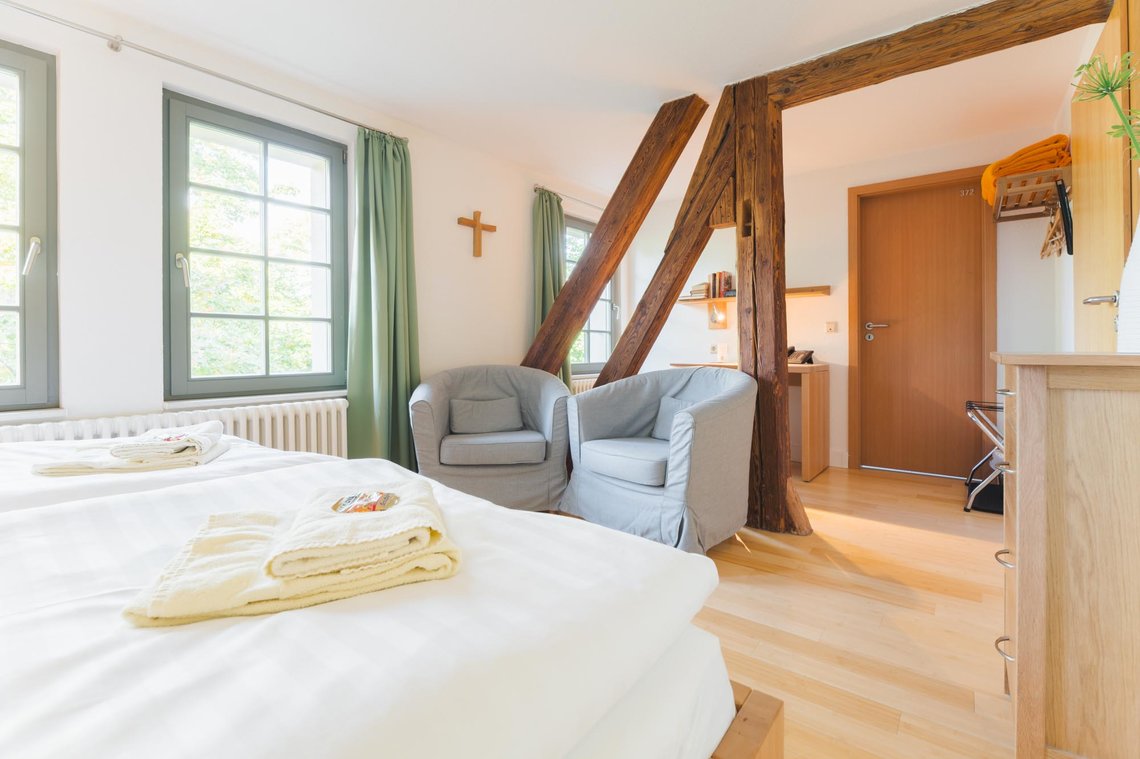 Zwei Sessel stehen in einem Raum mit Holzpfeilern und einem Schreibtisch