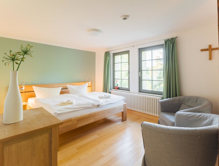 Ein Doppelbett und zwei Sessel stehen in einem Raum mit einer grünen Wand und grünen Gardinen